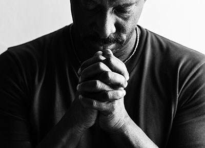 Person with clasped hands, bowed head